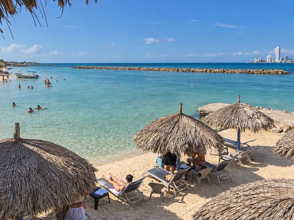 Playa resguardada de Paraíso del Sol en Tierra Bomba: bohíos, tumbonas, espolón y Bocagrande al fondo
