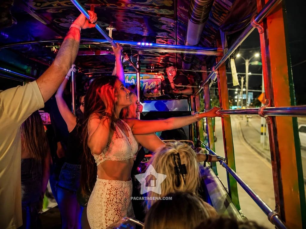 Pasajera bailando con los brazos en alto en la chiva rumbera nocturna de Cartagena