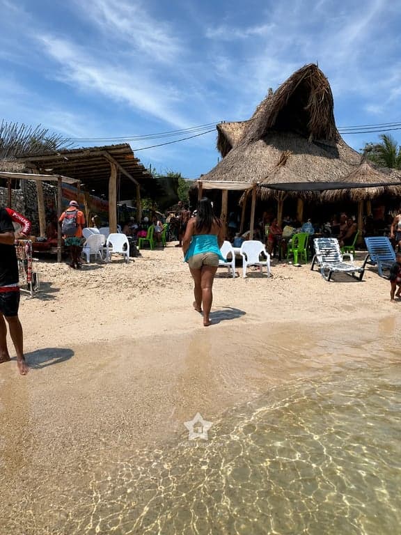 Orilla de agua clara frente a los kioscos de palma de Punta Arena, Tierra Bomba