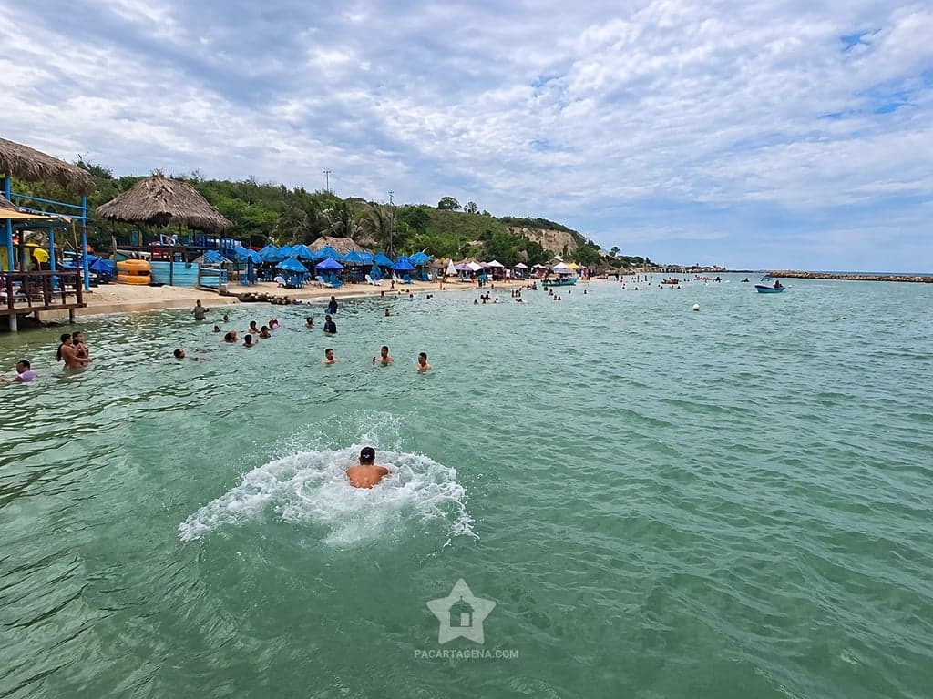 Bañistas frente a la playa y los bohíos de Paraíso del Sol en Paraíso del Sol, Tierra Bomba.