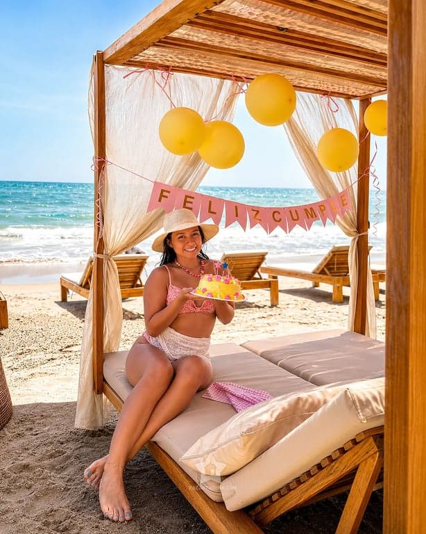 Celebración de cumpleaños con globos en una cama con dosel frente al mar, en Playa Linda