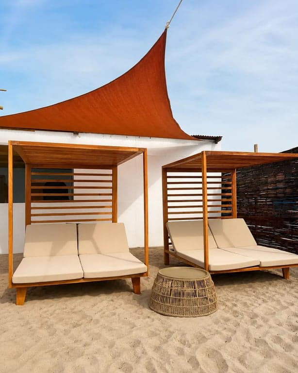 Cabañas gemelas de teca con camas y vela terracota en Nakawa Beach Club.