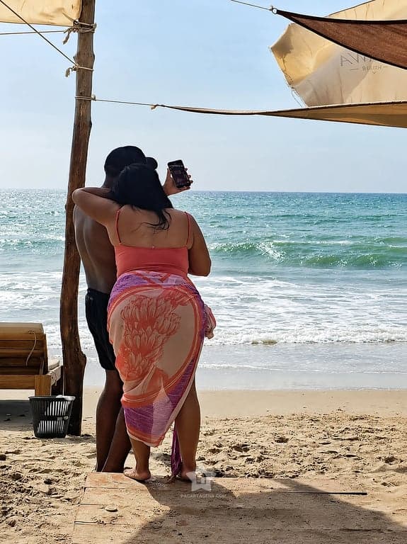 Pareja tomando una foto frente al mar desde la zona de sombra, en Playa Linda