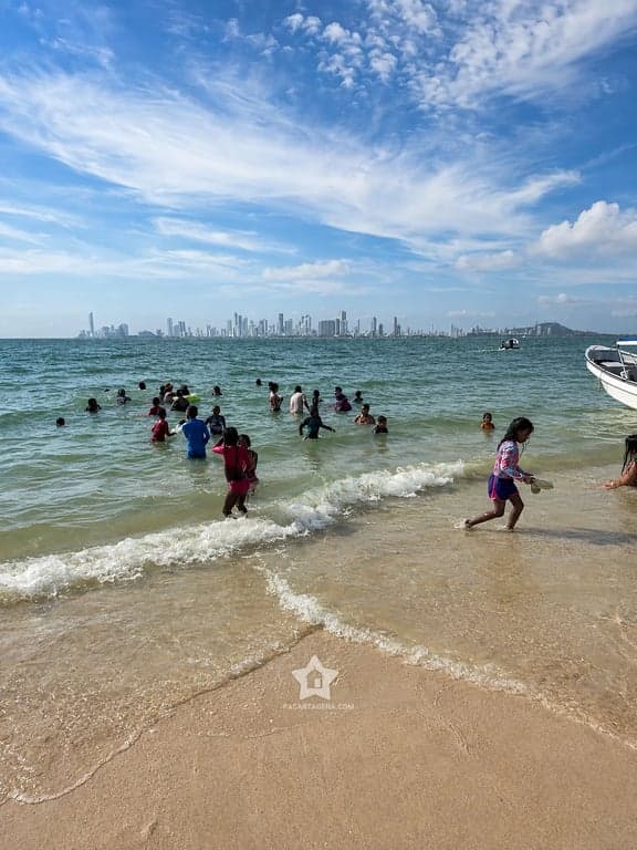 Orilla de Punta Arena con bañistas y la ciudad de Cartagena en el horizonte