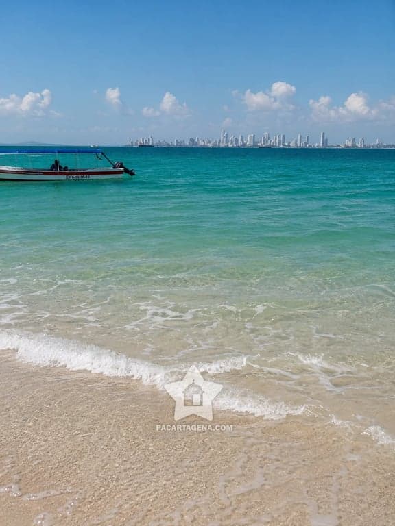Orilla de Punta Arena en Tierra Bomba: arena clara, mar turquesa y Cartagena al fondo
