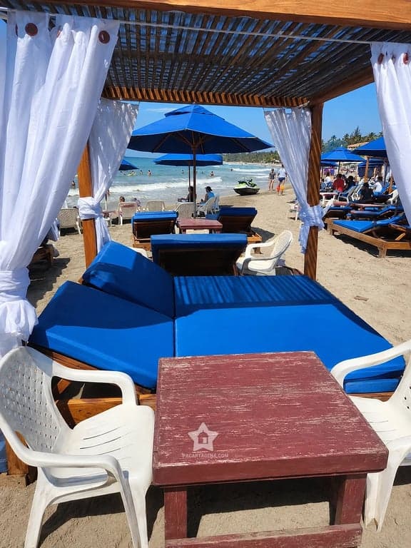 Cama doble con dosel frente al mar en Playa Linda: sombra, colchoneta y mesa en el pasadía