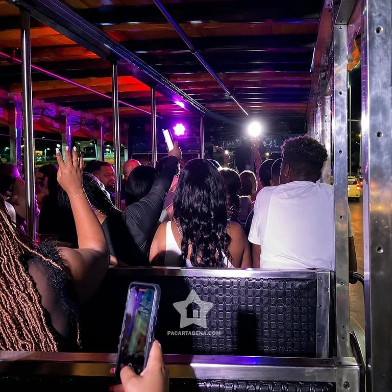 Fiesta a bordo de la chiva rumbera con luces de colores durante el recorrido nocturno