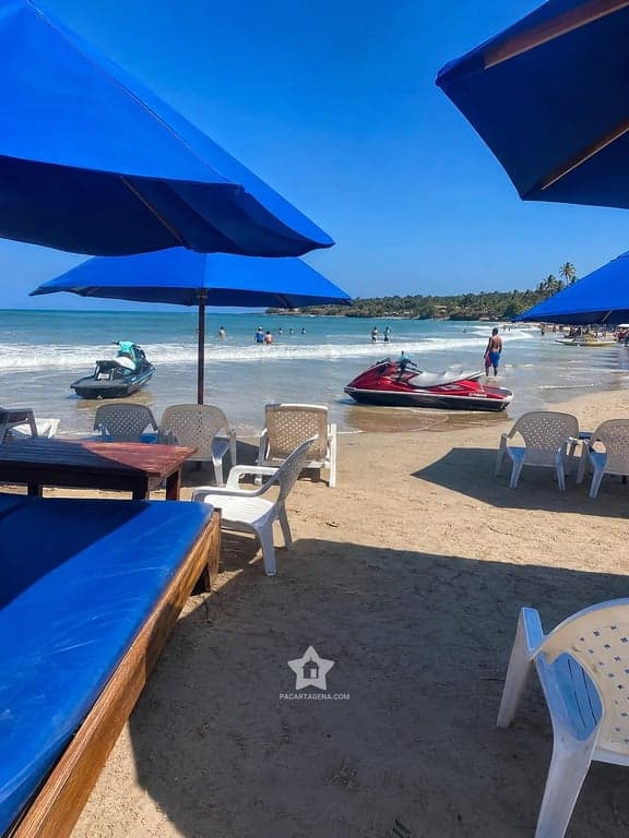 Sombrillas azules y motos de agua en la orilla de Playa Linda, isla de Tierra Bomba