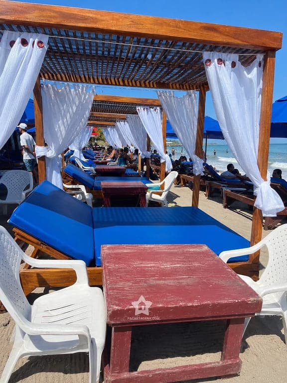 Cama con dosel, cortinas blancas y mesa en la arena de Playa Linda, isla de Tierra Bomba