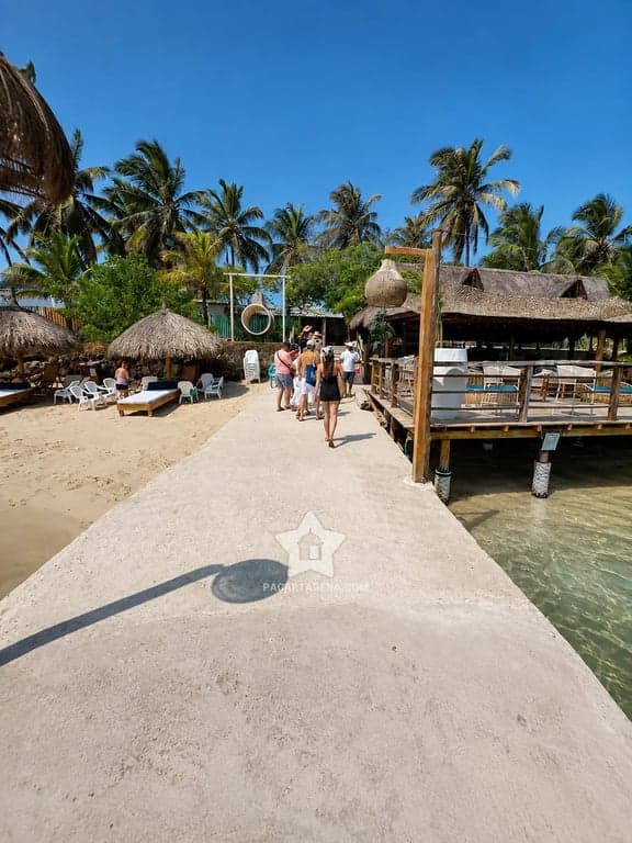 Llegada al club por el muelle, con kioscos de palma y el mar de Tierra Bomba