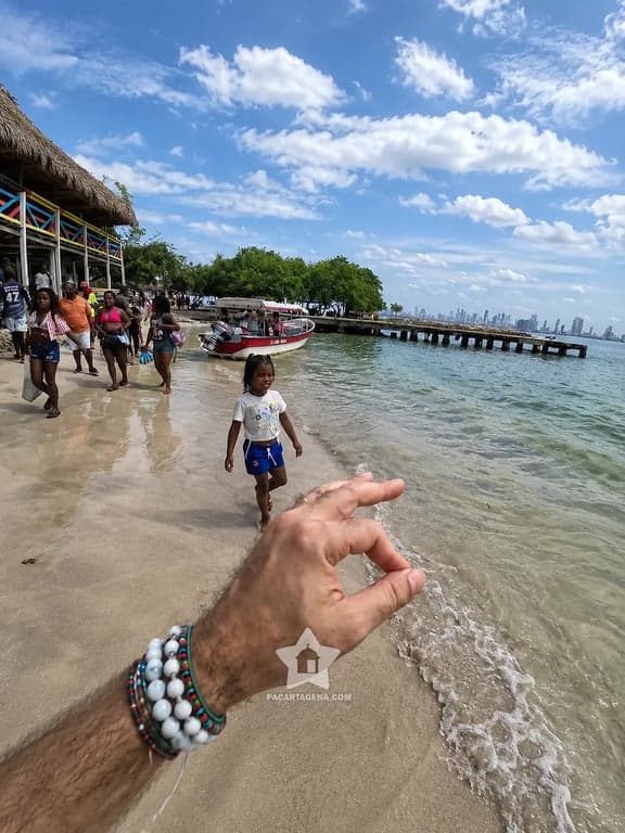 Orilla de Punta Arena con chozas y lanchas, y el skyline de Cartagena al fondo