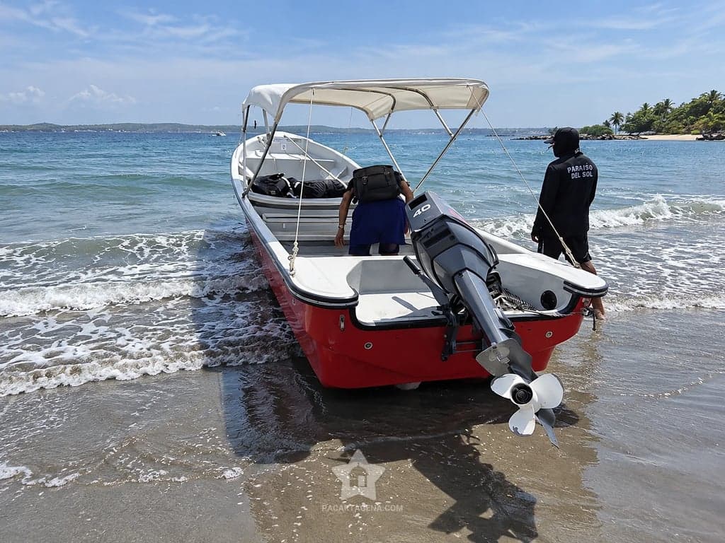 Lancha roja y blanca con techo detenida en la orilla de la playa en Paraíso del Sol, Tierra Bomba.