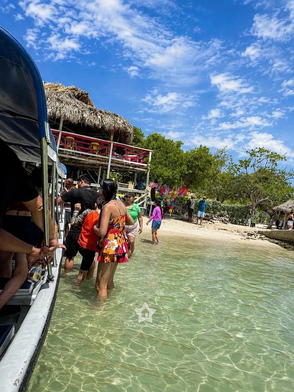 Llegada a Punta Arena: pasajeros bajando de la lancha en agua clara, Tierra Bomba