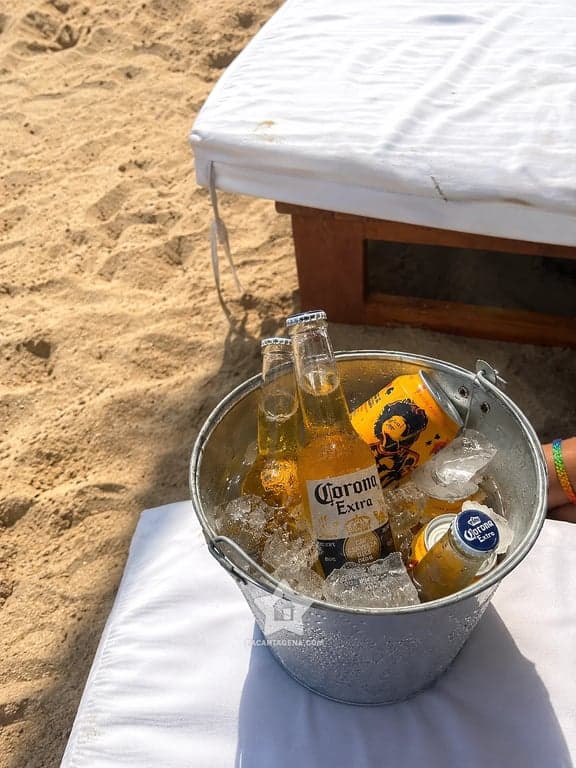 Bebidas frías en balde con hielo junto a la cama de playa en Tierra Bomba