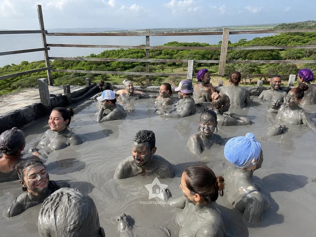 Cráter de lodo del Volcán del Totumo lleno de gente feliz, con la laguna al fondo