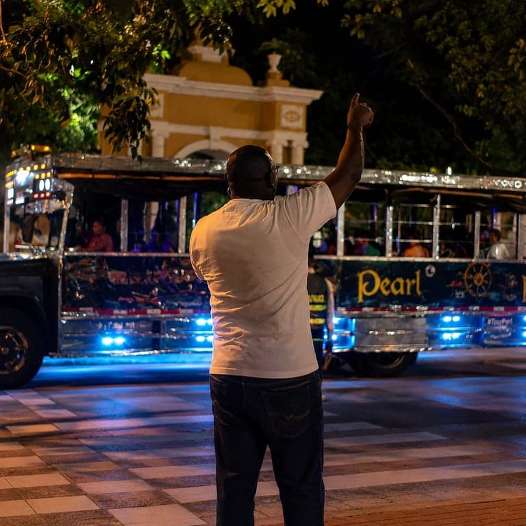 Chiva rumbera iluminada de noche en Cartagena con su animador, lista para el recorrido nocturno