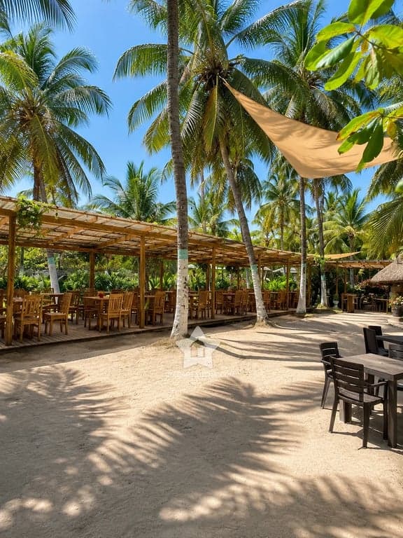 Zona de mesas bajo velas de sombra y palmeras en Palmarito Beach Club