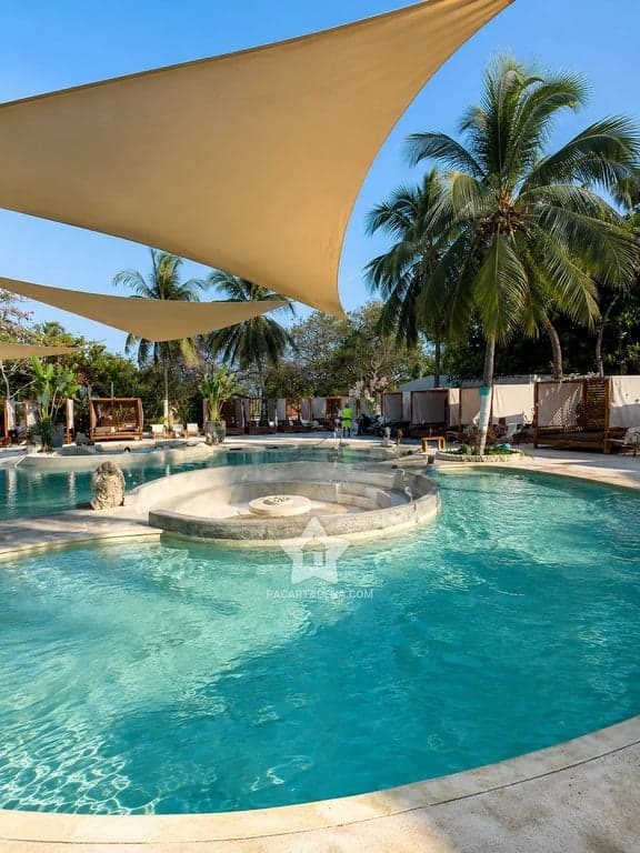 Piscina y zona de descanso bajo velas de sombra en Palmarito Beach Club, Tierra Bomba