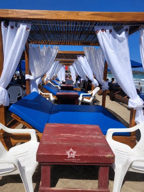 Cama con dosel y mesa de madera en Playa Linda: el espacio que se reserva en el pasadía