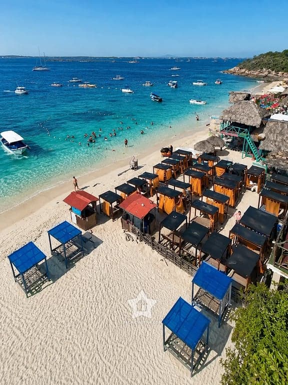 Playa de aguas turquesa con carpas y lanchas en las Islas del Rosario