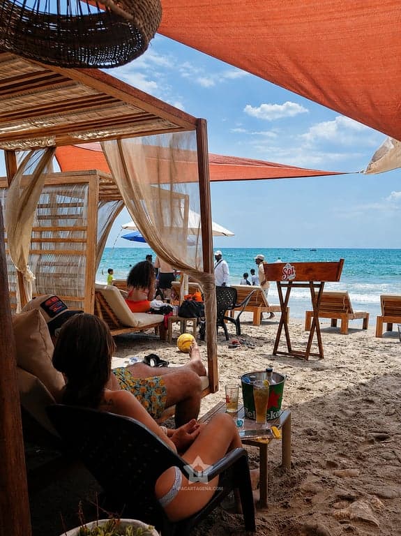 Zona de descanso con cortinas blancas y vista al mar turquesa de Playa Linda, en Tierra Bomba