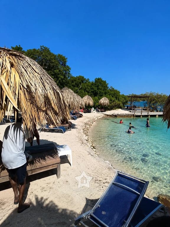 Orilla de arena con chozas de palma y baño en aguas poco profundas, isla del Rosario